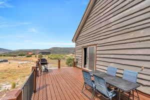 Wooden deck featuring a mountain view, grilling area, and outdoor dining space