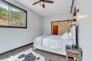 Carpeted bedroom featuring a barn door and a ceiling fan