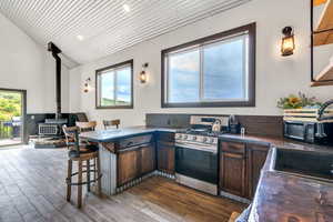 Kitchen featuring a peninsula, a breakfast bar area, a wood stove, stainless steel gas stove, and decorative backsplash