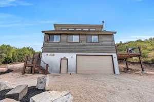 View of front of house featuring stairway, an attached garage, driveway, and a deck
