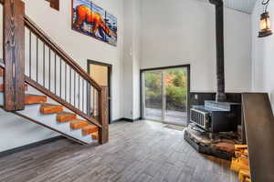 Entrance foyer with a wood stove, a high ceiling, wood tiled floors, and stairs