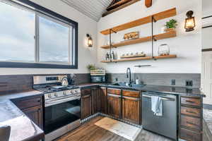 Kitchen with appliances with stainless steel finishes, dark wood-type flooring, decorative backsplash, open shelves, and dark brown cabinetry