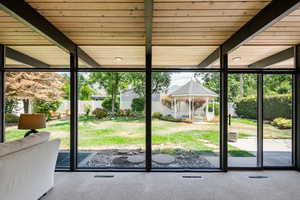 Doorway to outside with a wall of windows and a wooden ceiling with exposed beams