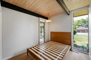 Unfurnished bedroom featuring wood finished floors and a wood ceiling with exposed beams