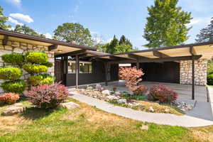 View of front facade with stone siding, a carport, and a front lawn