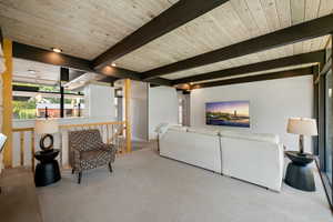 Living room with carpet flooring and a wood ceiling with exposed beams