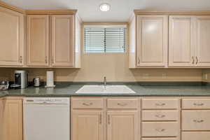 Kitchen featuring light brown cabinetry and dark countertops