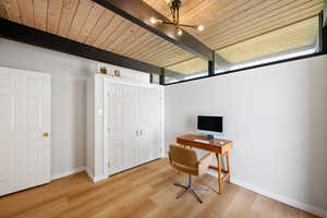 Home office featuring light wood-type flooring, a wood ceiling with exposed beams, and a chandelier