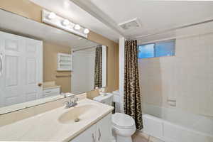 Bathroom featuring shower / bath combination with curtain, vanity, and light tile patterned flooring