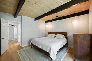 Bedroom featuring light wood-style floors and a wood ceiling with exposed beams