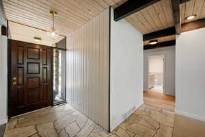Entryway featuring baseboards and a wood ceiling with exposed beams