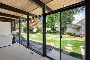 Doorway to outside with floor to ceiling windows, beamed ceiling, and carpet