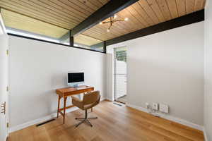 Office space with light wood-style floors and a wood ceiling with exposed beams