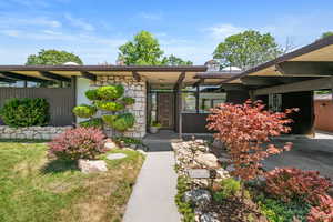 Entrance to property featuring stone siding and an attached carport