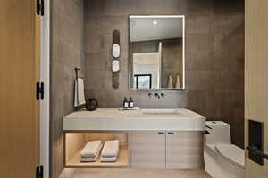 Bathroom with tile walls, vanity, and light tile patterned floors