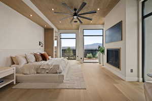 Bedroom featuring wood ceiling, a glass covered fireplace, a mountain view, light wood-type flooring, and recessed lighting