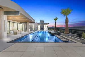 Pool at dusk with an infinity pool, a jacuzzi, and a patio area