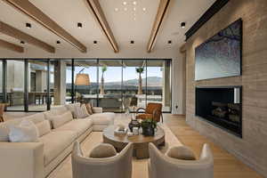 Living room with light wood-style floors, a fireplace, and beam ceiling