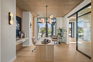Home office featuring light wood finished floors, a chandelier, and wooden ceiling