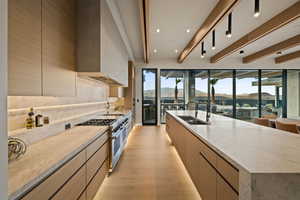 Kitchen with plenty of natural light, a mountain view, light stone counters, beamed ceiling, and recessed lighting