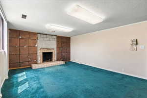 Unfurnished living room featuring a tile fireplace, carpet, and a textured ceiling