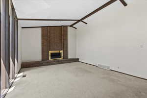 Unfurnished living room featuring a brick fireplace and carpet
