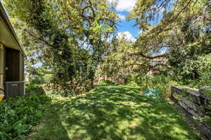 View of green lawn featuring view of wooded area