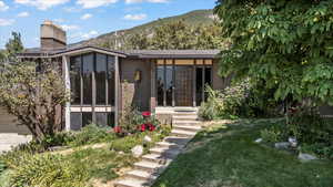 Rear view of property with a sunroom, brick siding, a mountain view, and a yard