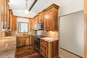 Kitchen featuring stainless steel appliances, backsplash, brown cabinetry, and pendant lighting