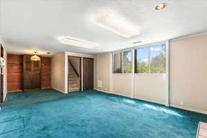 Spare room with stairs, a textured ceiling, and carpet flooring