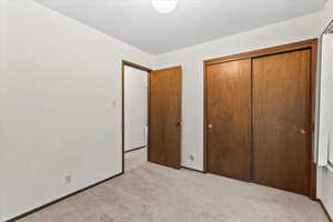 Unfurnished bedroom with a closet and light carpet