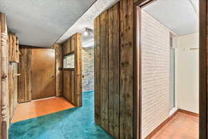 Corridor with tile patterned flooring, a textured ceiling, and carpet