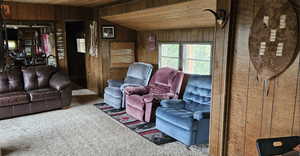 Living room with wood walls, wooden ceiling, carpet floors, and vaulted ceiling