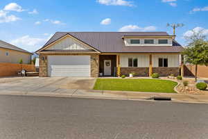 View of front of property with board and batten siding, stone siding, a garage, and a porch