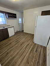 Kitchen featuring dark brown cabinets, white appliances, dark wood-style flooring, and open shelves