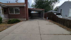 View of property exterior featuring a chimney, brick siding, a carport, and concrete driveway