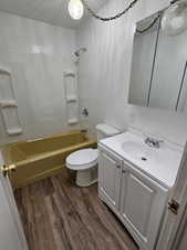 Bathroom featuring a textured ceiling, washtub / shower combination, dark wood-type flooring, and vanity