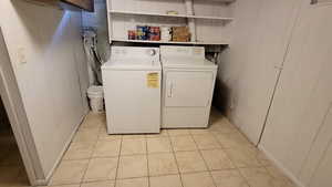 Laundry area featuring wood walls, light tile patterned floors, and washer and clothes dryer