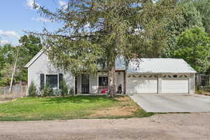 View of front of home featuring concrete driveway, a garage, and a metal roof