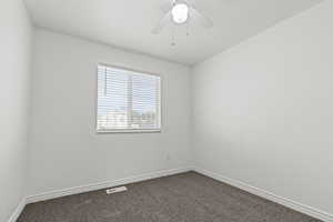 Carpeted spare room with a textured ceiling and ceiling fan