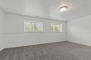 Carpeted spare room featuring a textured ceiling