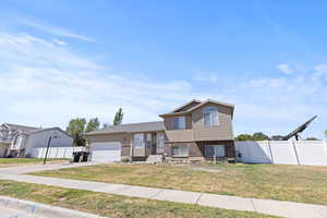 Tri-level home featuring brick siding, a garage, and concrete driveway