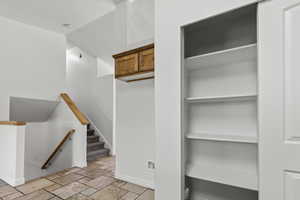 Staircase featuring stone tile flooring and baseboards