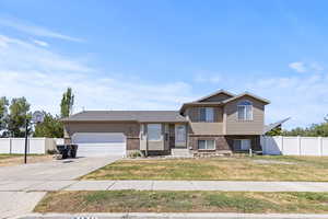 Tri-level home with concrete driveway, brick siding, and an attached garage