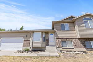 Split level home featuring brick siding, a garage, and driveway