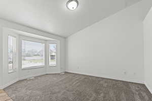 Spare room with vaulted ceiling, carpet, and a textured ceiling