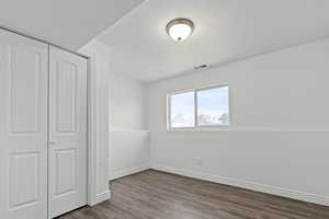 Unfurnished bedroom featuring dark wood-style floors and a closet