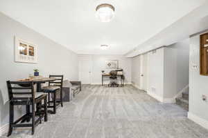 Dining space with a desk, light carpet, and stairs
