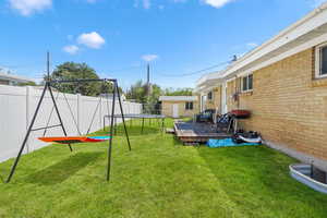 Fenced backyard with a trampoline and a wooden deck