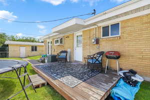 Wooden deck featuring a lawn, a grill, and a trampoline